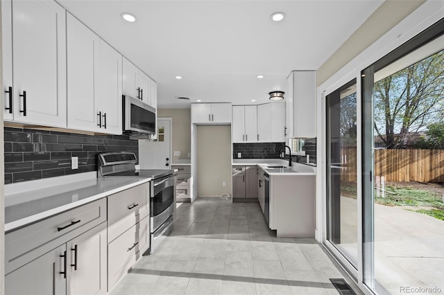 kitchen with a sink, stainless steel appliances, visible vents, light countertops, and tasteful backsplash