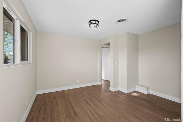 unfurnished room featuring visible vents, wood finished floors, and baseboards