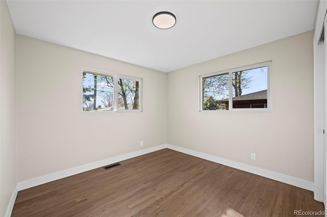 unfurnished room with wood finished floors, baseboards, and a healthy amount of sunlight