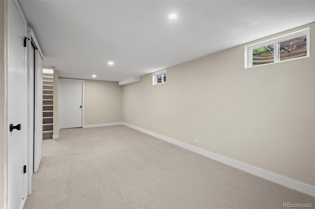 below grade area with plenty of natural light, light carpet, baseboards, and recessed lighting