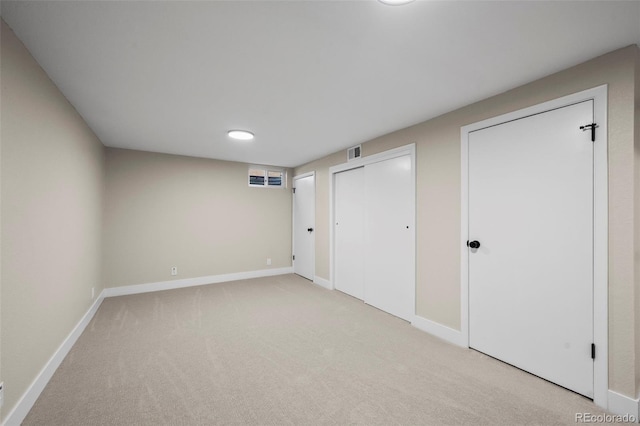 unfurnished bedroom with light carpet, baseboards, visible vents, and multiple closets