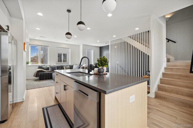 3101 W 47th Ave Unit 14, Denver, CO 80211 - kitchen with stainless steel appliances, a sink, dark countertops, a center island with sink, and light wood finished floors