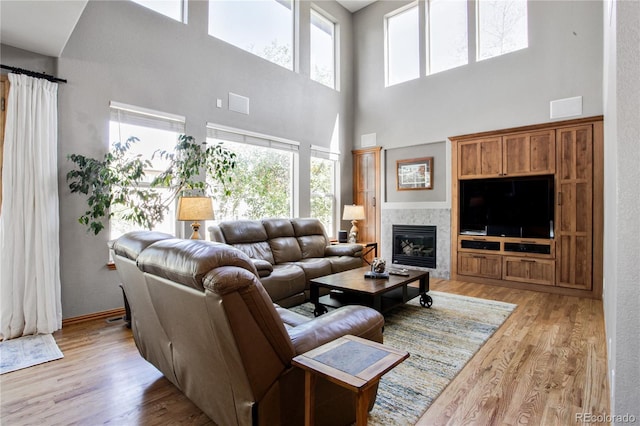 9644 S Estes Way, Littleton, CO 80127 - living room featuring a high ceiling, plenty of natural light, light wood-style floors, and a glass covered fireplace