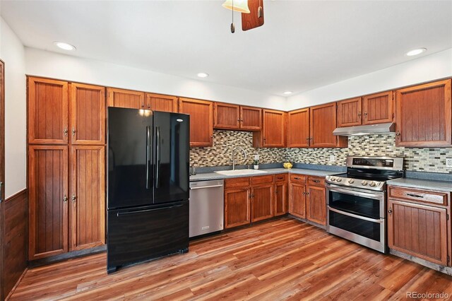 9125 Lowell Ct, Westminster, CO 80031 - kitchen featuring stainless steel appliances, under cabinet range hood, light wood finished floors, decorative backsplash, and brown cabinets