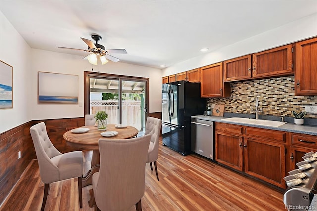 9125 Lowell Ct, Westminster, CO 80031 - kitchen with stainless steel dishwasher, black fridge, a ceiling fan, light wood-type flooring, and brown cabinetry