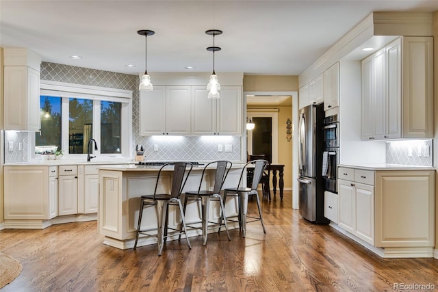 9980 Newton Ct, Westminster, CO 80031 - kitchen featuring stainless steel appliances, a center island, a kitchen bar, backsplash, and light countertops