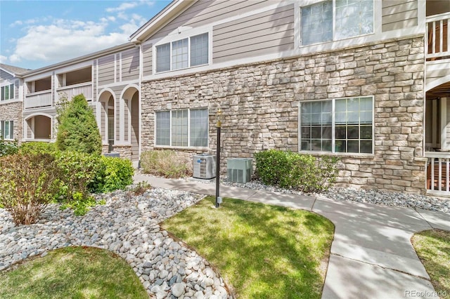 view of front facade with central AC unit and stone siding