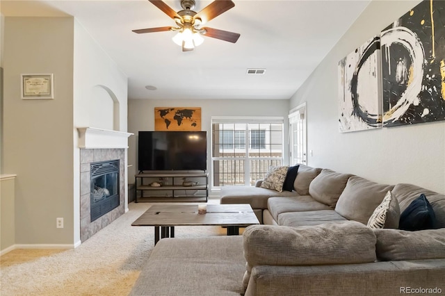living area featuring ceiling fan, visible vents, a tile fireplace, baseboards, and carpet