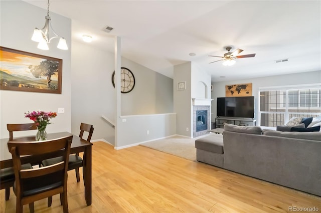living area with visible vents, light wood-style flooring, ceiling fan, and a fireplace