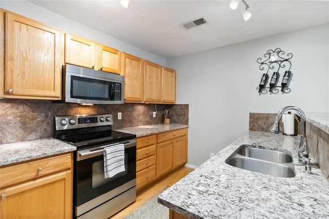 kitchen featuring visible vents, light brown cabinets, tasteful backsplash, a sink, and appliances with stainless steel finishes