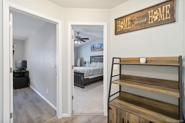 corridor with baseboards, lofted ceiling, and wood finished floors