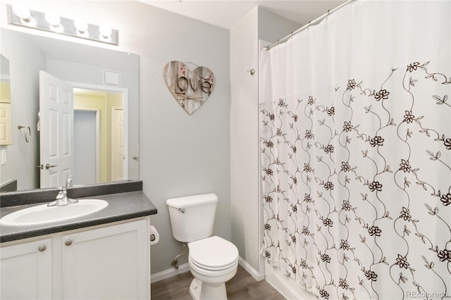 bathroom featuring vanity, toilet, a shower with shower curtain, baseboards, and wood finished floors