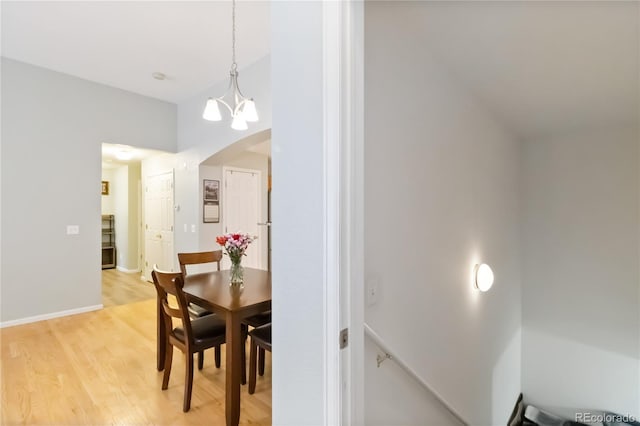 dining space featuring an inviting chandelier, baseboards, and light wood-style flooring
