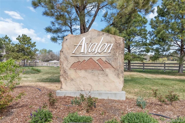 community / neighborhood sign featuring fence and a yard