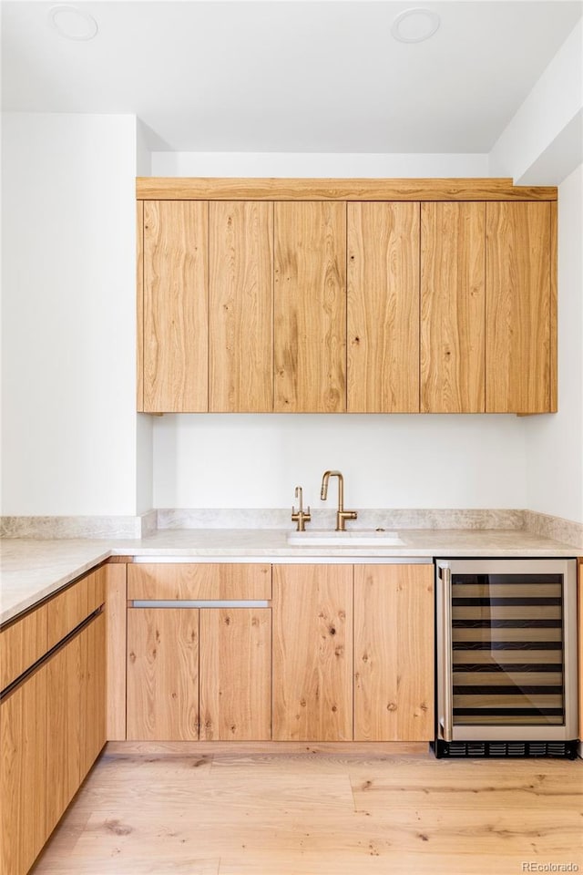 kitchen featuring wine cooler, light hardwood / wood-style flooring, light brown cabinets, and sink