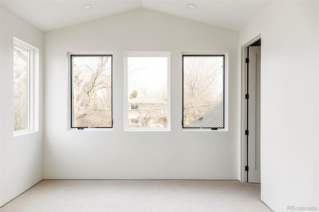 carpeted empty room with plenty of natural light and lofted ceiling