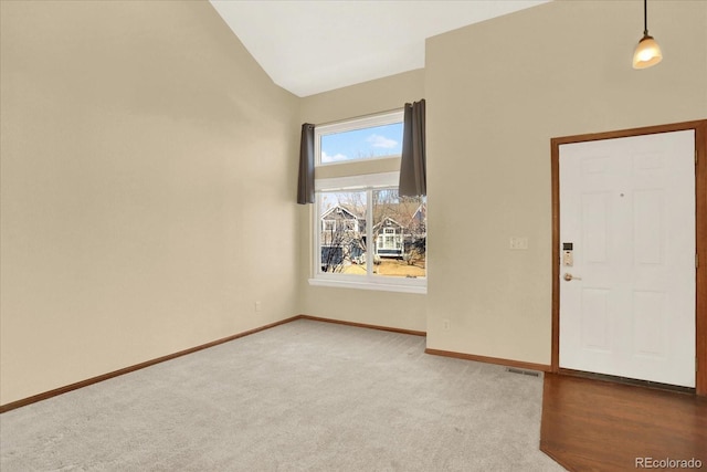 carpeted empty room with vaulted ceiling