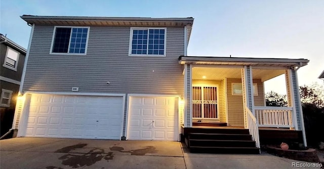 split level home with an attached garage, covered porch, and concrete driveway