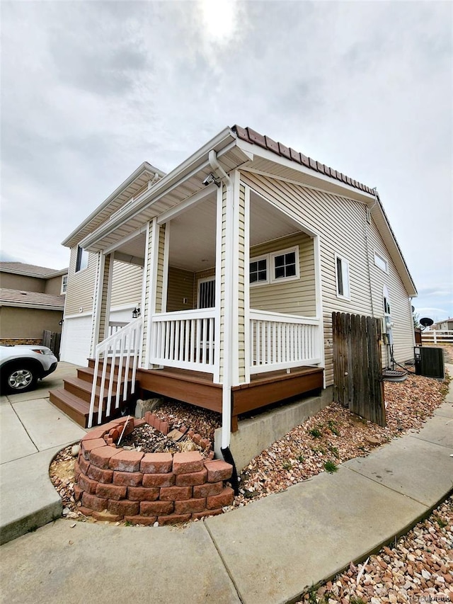 view of front of house with a garage, fence, concrete driveway, and covered porch