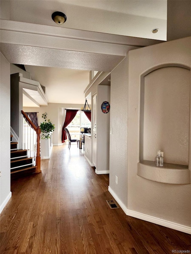 hall with baseboards, dark wood-style floors, visible vents, and stairs