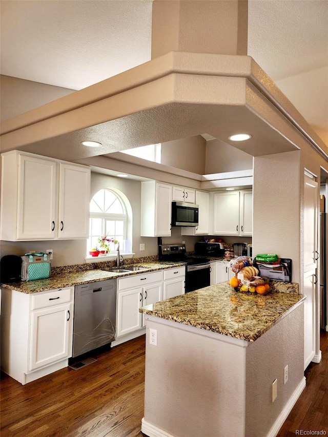 kitchen featuring white cabinets, a sink, stainless steel appliances, dark wood-type flooring, and light stone counters