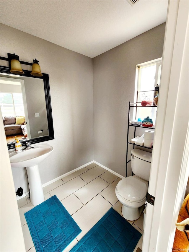 half bath featuring tile patterned floors, toilet, and baseboards