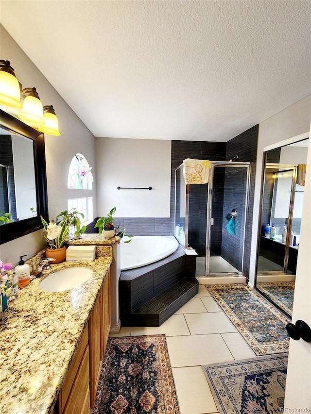 bathroom with a bath, vanity, a stall shower, and a textured ceiling
