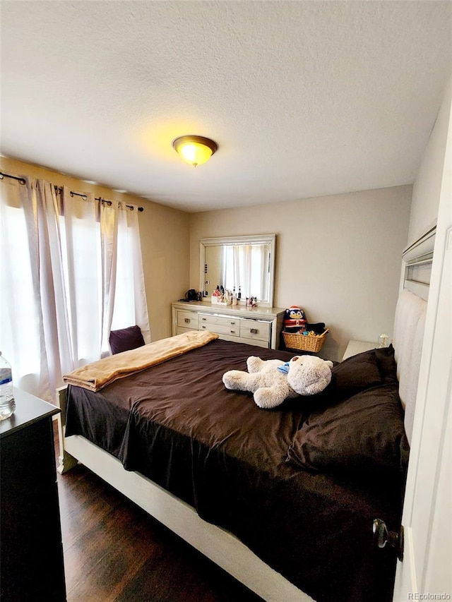 bedroom with a textured ceiling and dark wood finished floors