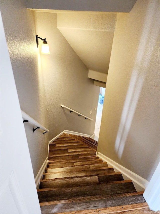 stairway featuring baseboards and wood finished floors