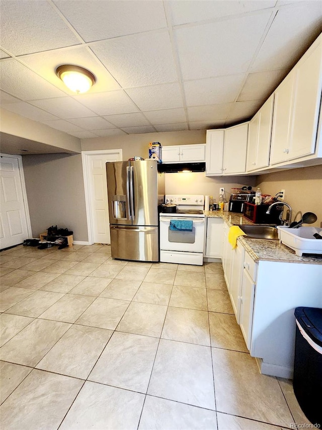 kitchen with a paneled ceiling, under cabinet range hood, white range with electric stovetop, a sink, and stainless steel fridge