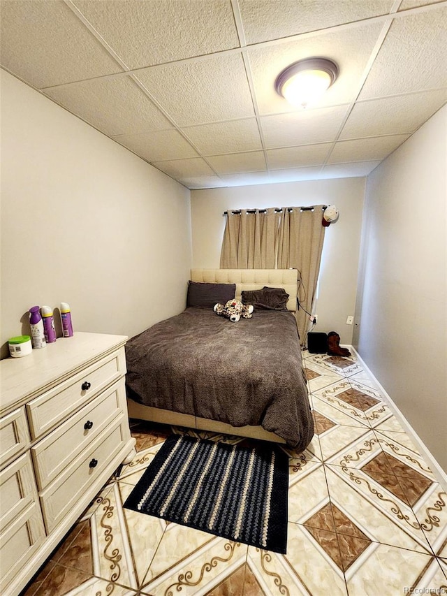 bedroom with light tile patterned floors and a drop ceiling