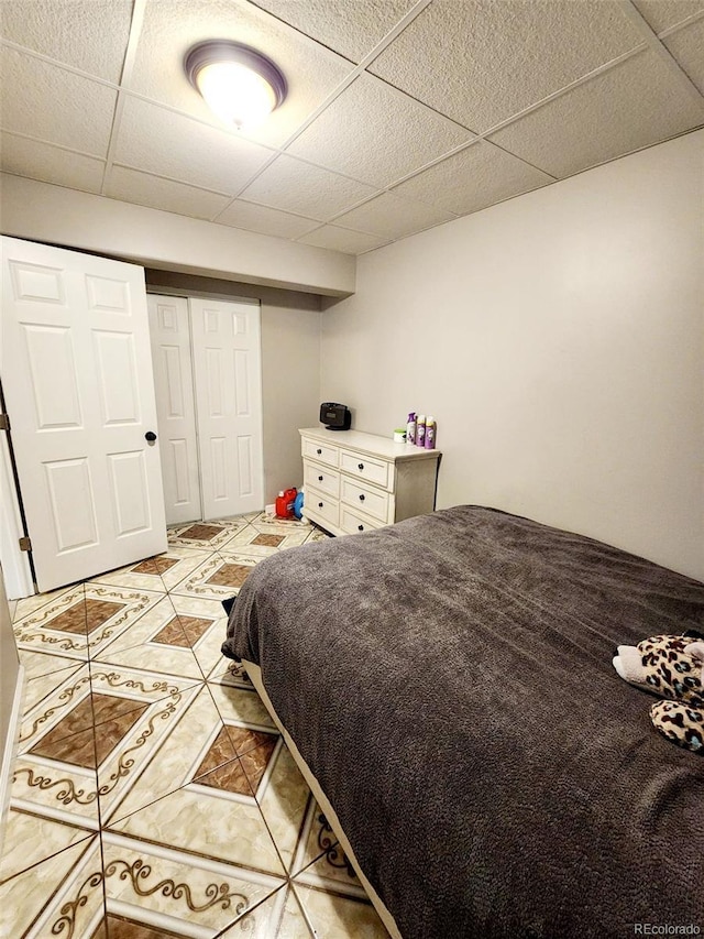 bedroom with a closet, a paneled ceiling, and light tile patterned flooring