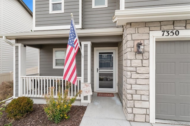 entrance to property featuring a garage and stone siding