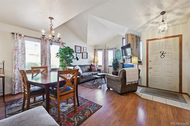 dining area with lofted ceiling, hardwood / wood-style floors, and a chandelier