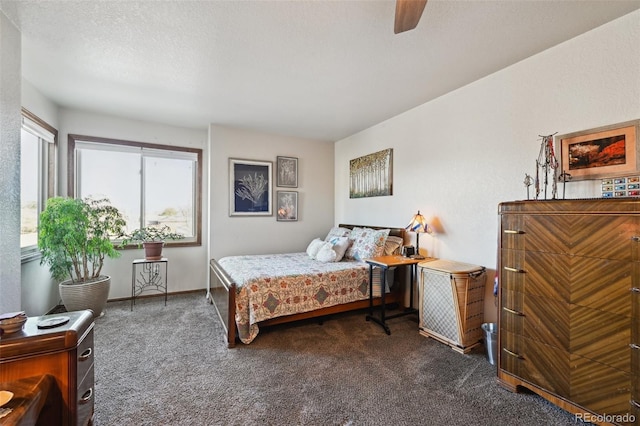 bedroom with a textured ceiling, ceiling fan, and dark colored carpet