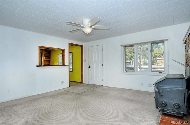 interior space featuring a wood stove, carpet, and ceiling fan