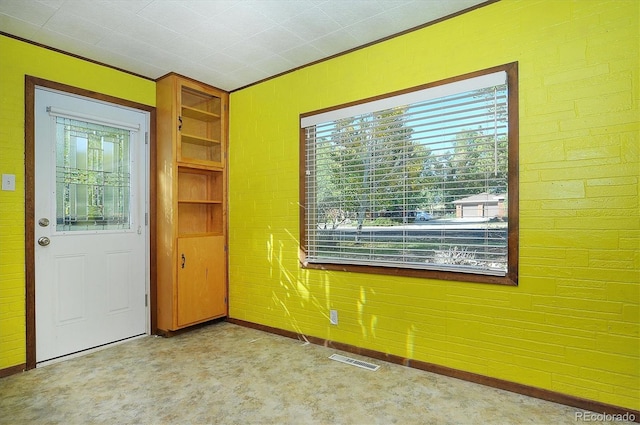 spare room featuring brick wall, light carpet, and a wealth of natural light