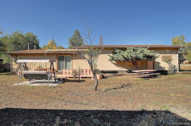 rear view of property with a wooden deck, a yard, and a patio