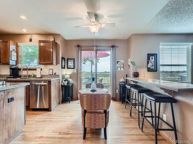 3691 Bucknell Dr, Highlands Ranch, CO 80129 - kitchen featuring stainless steel dishwasher, light wood-type flooring, a ceiling fan, healthy amount of natural light, and recessed lighting