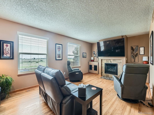 3691 Bucknell Dr, Highlands Ranch, CO 80129 - living room featuring light wood finished floors, healthy amount of natural light, a fireplace, and a textured ceiling