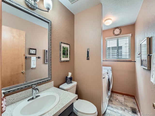 3691 Bucknell Dr, Highlands Ranch, CO 80129 - bathroom with washer and clothes dryer, stone tile floors, vanity, a textured wall, and a textured ceiling