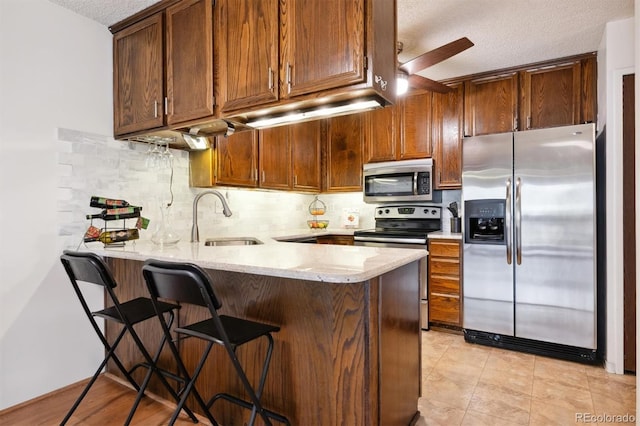 kitchen featuring appliances with stainless steel finishes, kitchen peninsula, sink, and a textured ceiling