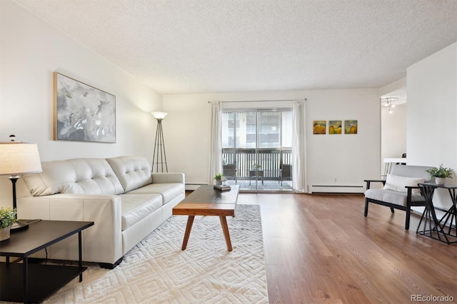 living room featuring a baseboard radiator, hardwood / wood-style floors, and a textured ceiling