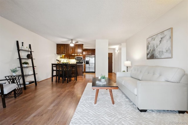 living room with wood-type flooring, a textured ceiling, sink, and ceiling fan