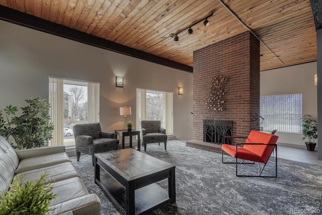 living room featuring track lighting, a fireplace, beam ceiling, and wood ceiling