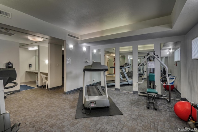 exercise room featuring a textured ceiling and carpet flooring