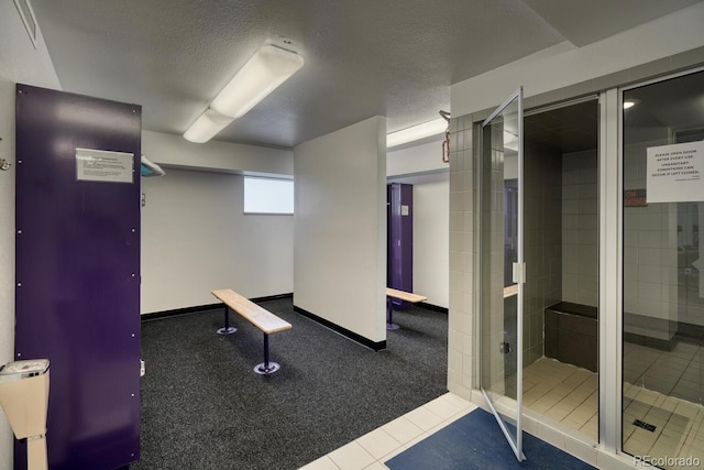 exercise area featuring tile patterned flooring and a textured ceiling