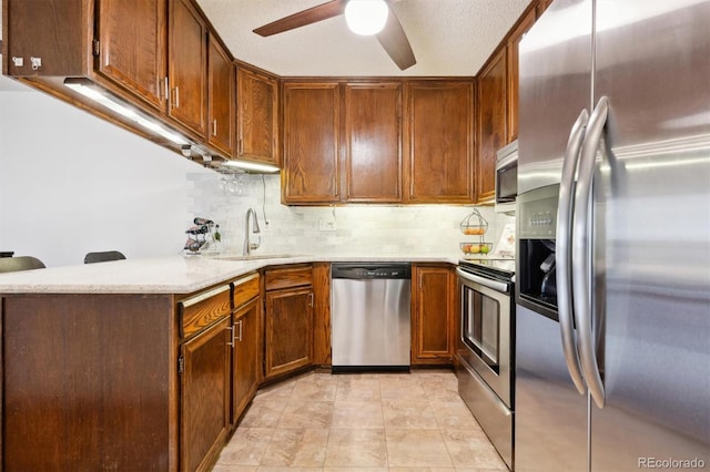 kitchen featuring sink, appliances with stainless steel finishes, kitchen peninsula, ceiling fan, and backsplash