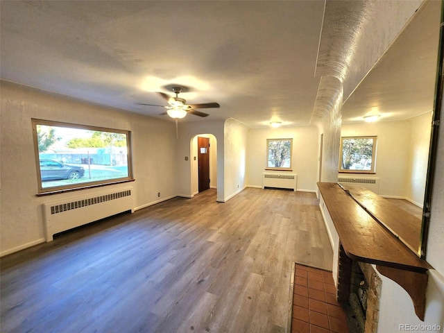 18 Columbia Dr, Julesburg, CO 80737 - unfurnished living room with radiator heating unit, wood finished floors, a ceiling fan, and arched walkways