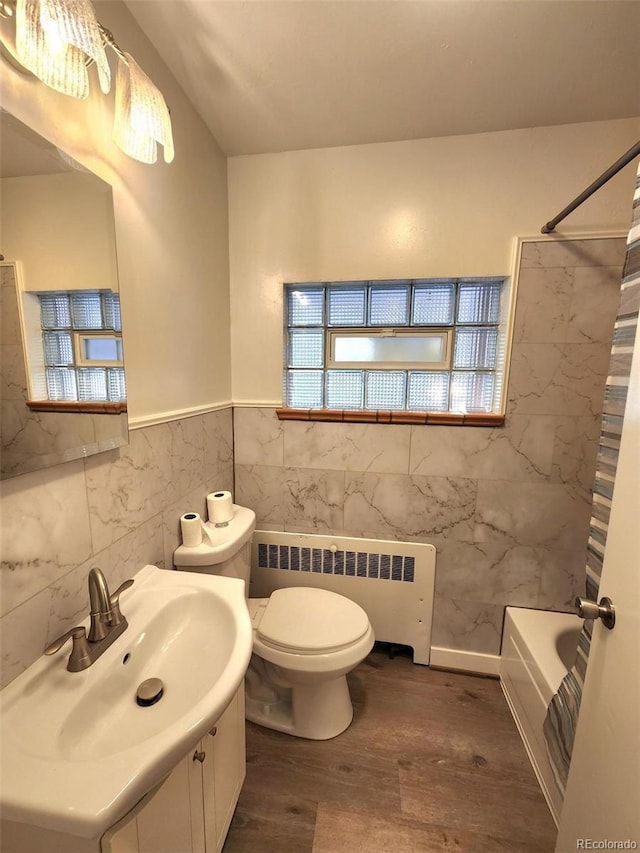 18 Columbia Dr, Julesburg, CO 80737 - bathroom featuring radiator heating unit, wood finished floors, toilet, tile walls, and vanity